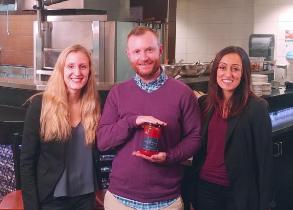 Photo of Laura Frielingsdorf, Tom Armitage and Kiran Bains holding a jar of tomato sauce.